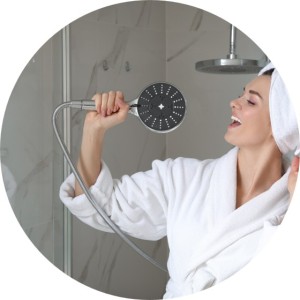 Woman in a bathrobe singing into a showerhead